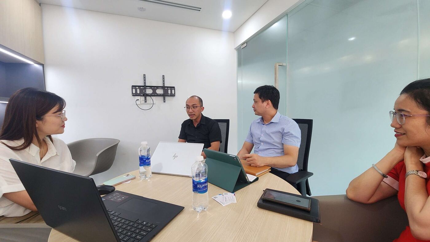 Nhân viên MONA họp trao đổi công việc quanh bàn tròn trong phòng họp